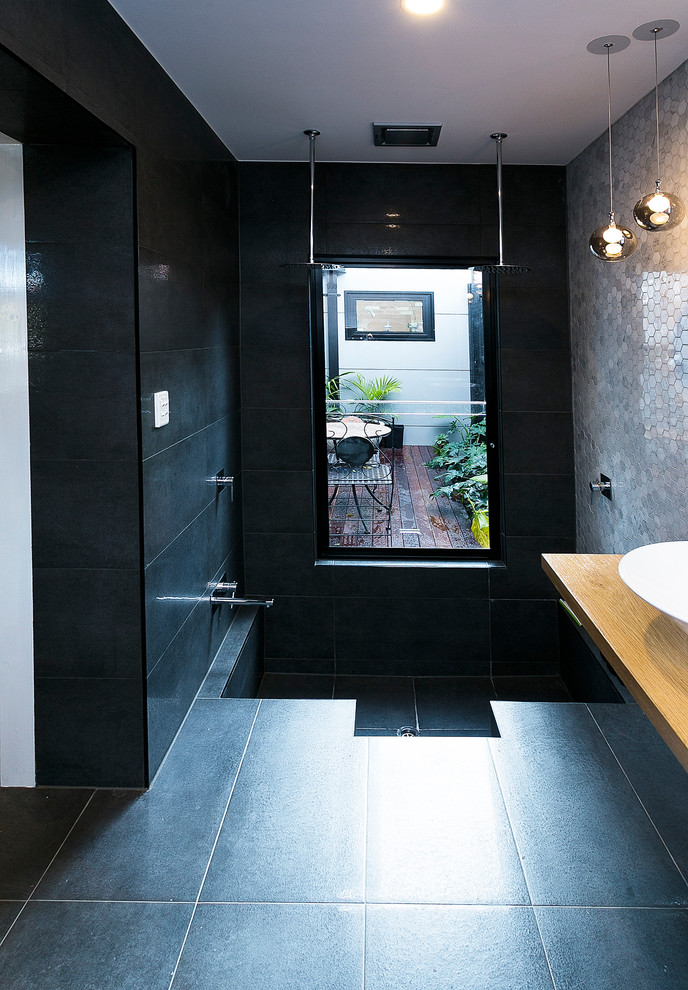 На фото: ванная комната среднего размера в современном стиле с стеклянными фасадами, белыми фасадами, столешницей из дерева, серой плиткой, каменной плиткой и душевой кабиной с