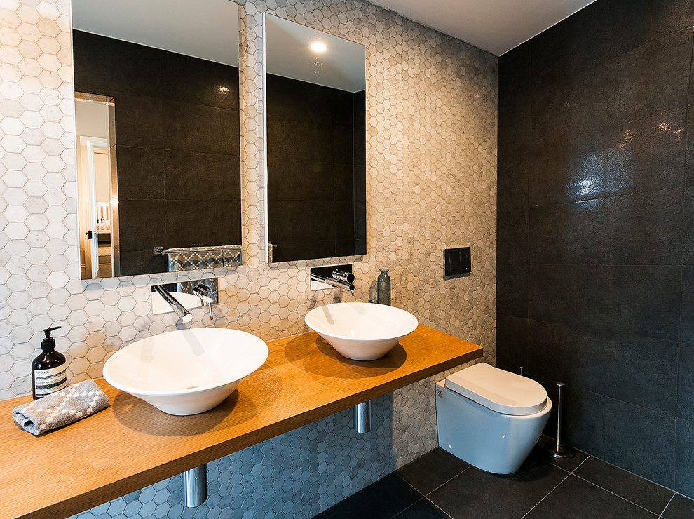 Immagine di una stanza da bagno con doccia contemporanea di medie dimensioni con ante di vetro, ante bianche, top in legno, piastrelle grigie e piastrelle in pietra