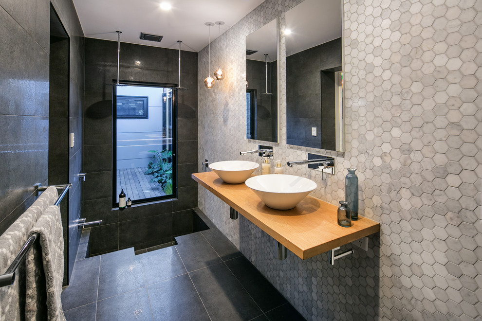 Modernes Duschbad mit Doppeldusche, grauen Fliesen, Aufsatzwaschbecken, Waschtisch aus Holz, offener Dusche und brauner Waschtischplatte in Melbourne