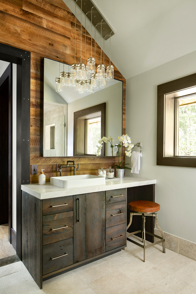 Imagen de cuarto de baño rural con armarios con paneles lisos, puertas de armario de madera en tonos medios, paredes grises, lavabo sobreencimera, suelo beige, encimeras grises y espejo con luz