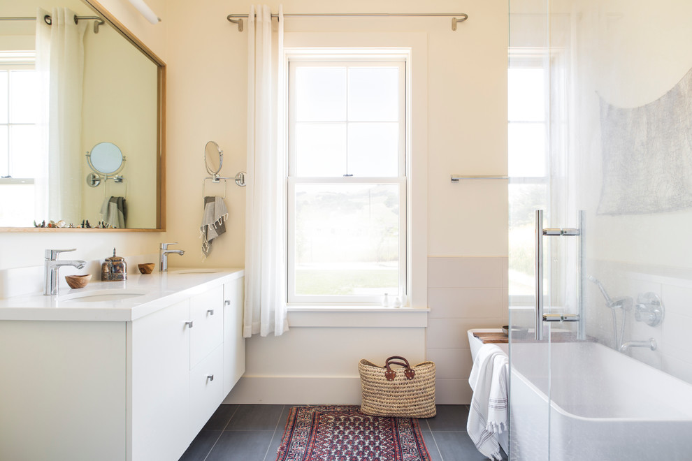 Photo of a large rural ensuite bathroom in San Francisco with flat-panel cabinets, white cabinets, a corner shower, beige walls, porcelain flooring, a submerged sink, grey floors and a hinged door.