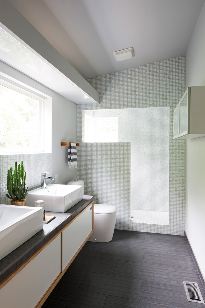 На фото: ванная комната в современном стиле с плоскими фасадами, белыми фасадами, зеленой плиткой, настольной раковиной и коричневой столешницей