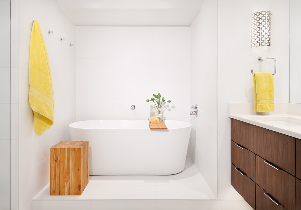 Ispirazione per una stanza da bagno design con ante lisce, ante in legno bruno, vasca freestanding, piastrelle bianche, pareti bianche, lavabo sottopiano, pavimento bianco e top bianco