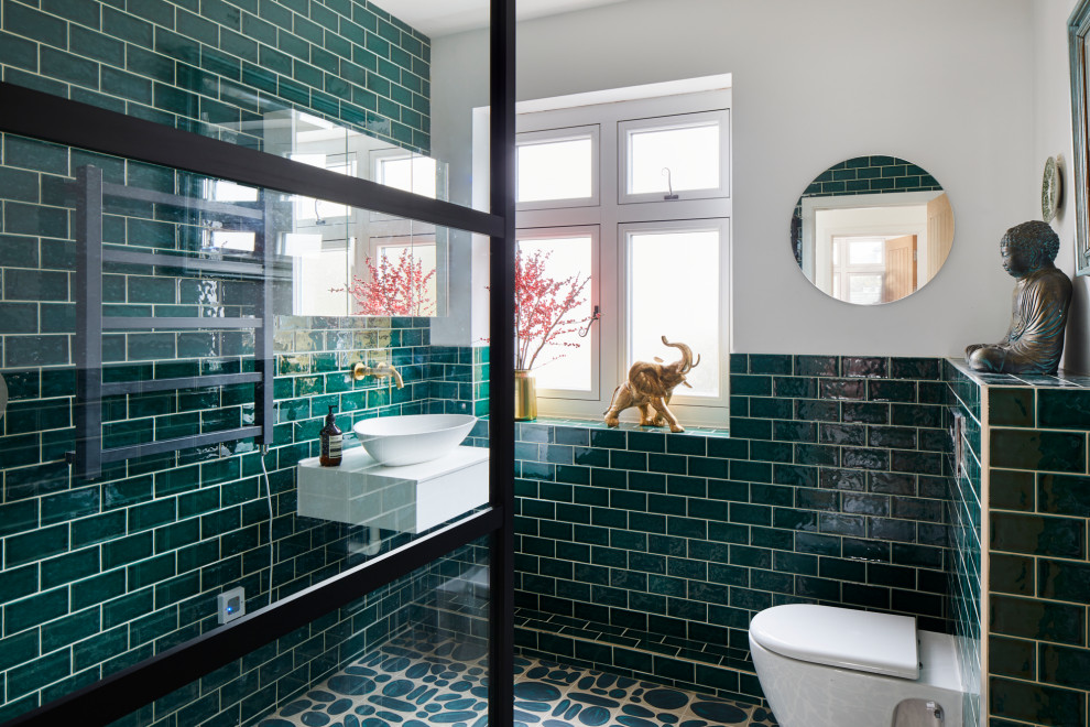 Foto på ett mellanstort funkis vit badrum med dusch, med öppna hyllor, vita skåp, en hörndusch, en vägghängd toalettstol, grön kakel, tunnelbanekakel, vita väggar, klinkergolv i keramik, ett fristående handfat, grönt golv och med dusch som är öppen