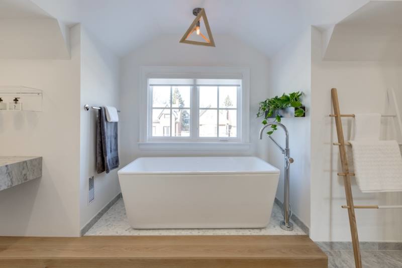 Ejemplo de cuarto de baño principal contemporáneo de tamaño medio con bañera exenta, baldosas y/o azulejos grises, baldosas y/o azulejos de piedra, paredes blancas, suelo de mármol, lavabo bajoencimera y encimera de mármol