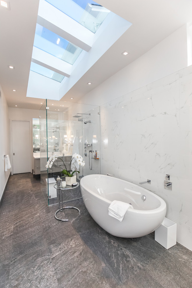 Cette image montre une grande salle de bain principale design avec une baignoire indépendante, une douche ouverte, WC à poser, un carrelage blanc, un mur blanc, un lavabo posé, un sol noir et aucune cabine.
