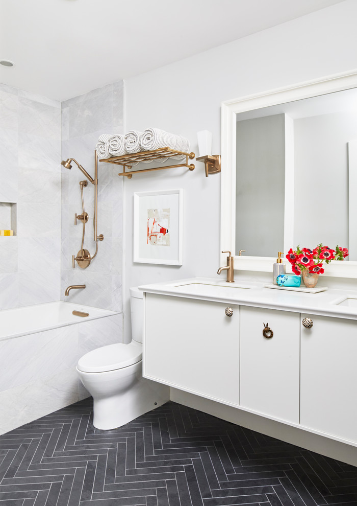 Foto di una stanza da bagno tradizionale con ante lisce, ante bianche, vasca ad alcova, vasca/doccia, piastrelle grigie, pareti bianche, lavabo sottopiano, pavimento nero e top bianco