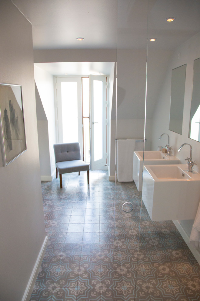 Diseño de cuarto de baño principal moderno con bañera exenta, sanitario de pared, baldosas y/o azulejos azules, baldosas y/o azulejos de cemento, paredes blancas, suelo con mosaicos de baldosas y lavabo suspendido