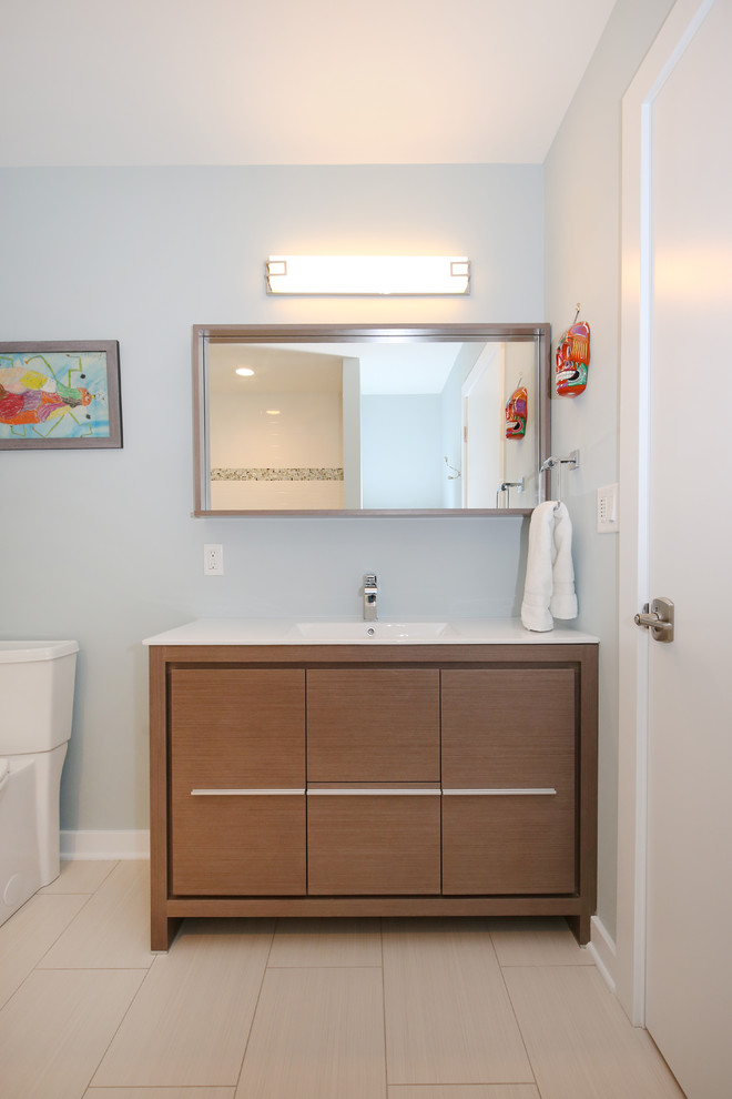Medium sized modern shower room bathroom in Grand Rapids with freestanding cabinets, light wood cabinets, an alcove bath, a one-piece toilet, white tiles, ceramic tiles, blue walls, ceramic flooring, an integrated sink and engineered stone worktops.
