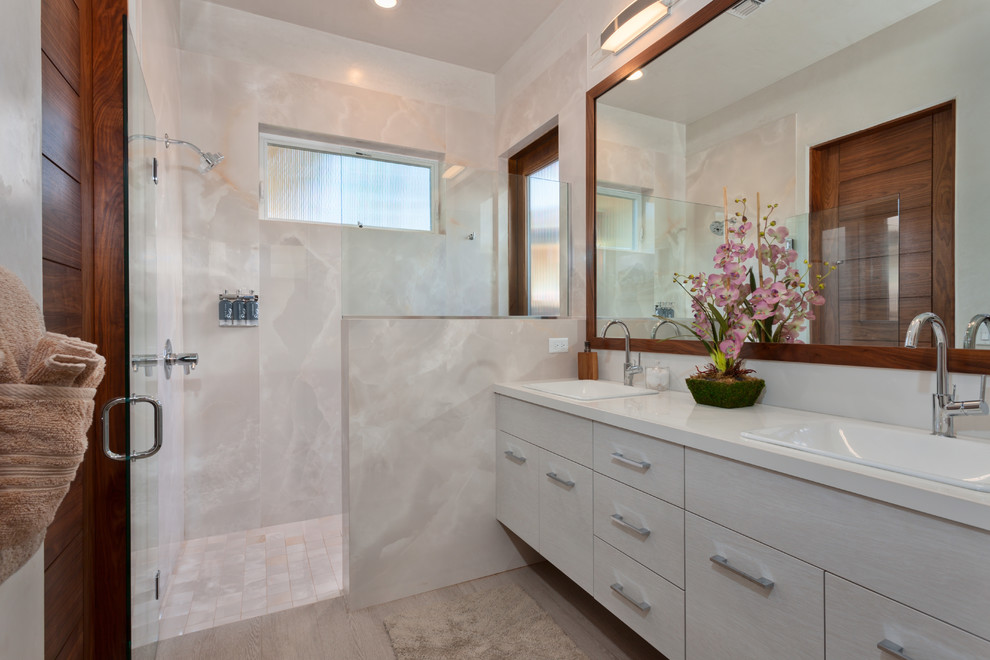 Bild på ett mellanstort funkis en-suite badrum, med klinkergolv i porslin, släta luckor, vita skåp, en dusch/badkar-kombination, vit kakel, stenhäll, vita väggar, ett nedsänkt handfat, bänkskiva i kvarts, dusch med gångjärnsdörr och beiget golv