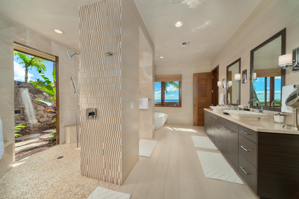 Large trendy master beige tile and porcelain tile beige floor and porcelain tile bathroom photo in Hawaii with flat-panel cabinets, dark wood cabinets, beige walls, a vessel sink and limestone countertops