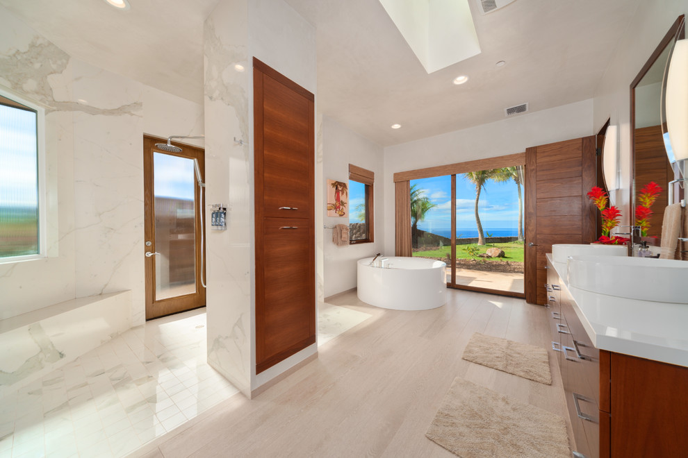 Medium sized contemporary ensuite bathroom in Hawaii with porcelain flooring, flat-panel cabinets, brown cabinets, a freestanding bath, a walk-in shower, a one-piece toilet, pebble tiles, white walls, a vessel sink, engineered stone worktops, beige floors and an open shower.
