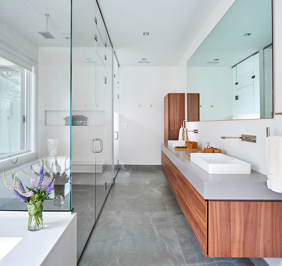 Design ideas for a contemporary ensuite bathroom in New York with flat-panel cabinets, medium wood cabinets, a built-in shower, white walls, a vessel sink, concrete worktops, grey floors, a hinged door and grey worktops.