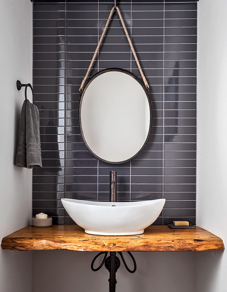 Idées déco pour une salle de bain moderne en bois vieilli avec un placard sans porte, un carrelage noir, des carreaux de céramique, un mur blanc, une vasque, un plan de toilette en bois et un plan de toilette marron.