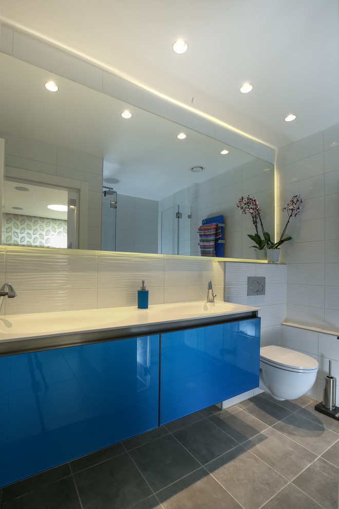 Свежая идея для дизайна: маленькая главная ванная комната в стиле модернизм с стеклянными фасадами, синими фасадами, белой плиткой, керамогранитной плиткой, белыми стенами, полом из керамогранита, стеклянной столешницей, серым полом и белой столешницей для на участке и в саду - отличное фото интерьера