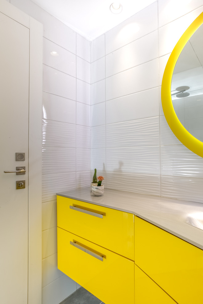 Idée de décoration pour une petite salle de bain minimaliste pour enfant avec un placard à porte vitrée, des portes de placard jaunes, un carrelage blanc, des carreaux de porcelaine, un mur blanc, un sol en carrelage de porcelaine, un sol gris, un plan de toilette en verre et un plan de toilette blanc.