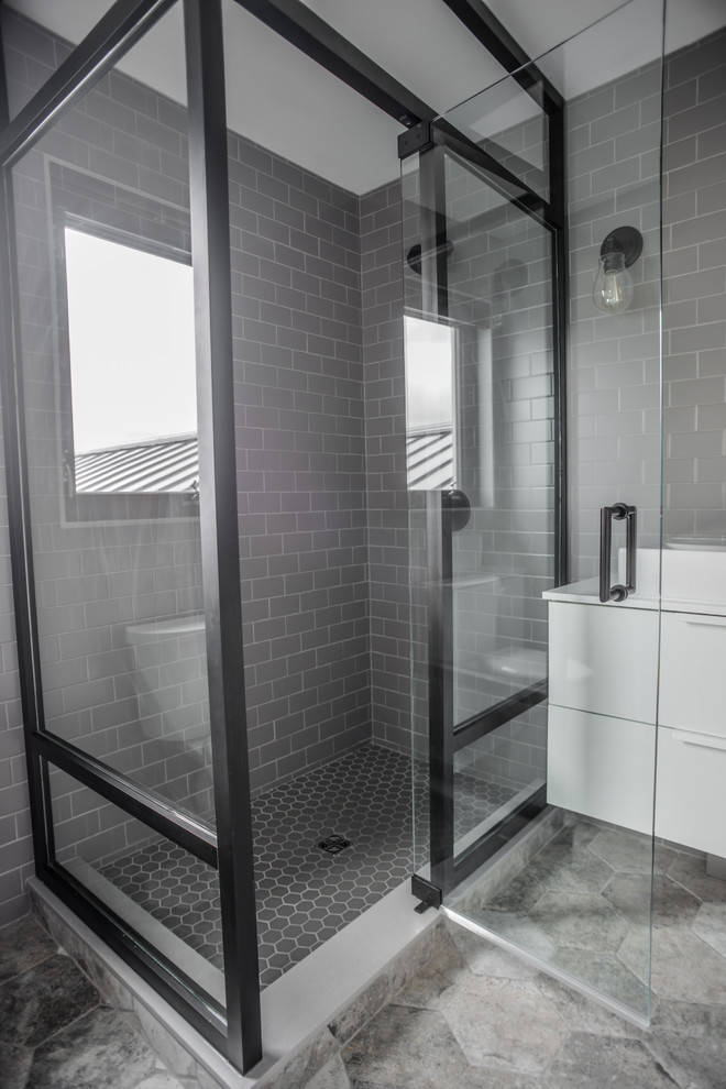 Idées déco pour une salle de bain contemporaine de taille moyenne avec un placard à porte plane, des portes de placard blanches, une douche d'angle, un carrelage gris, un carrelage métro, un mur gris, un sol en carrelage de céramique, une vasque et un plan de toilette en surface solide.