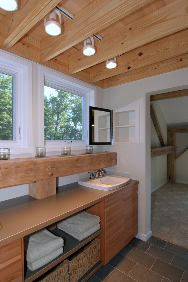Idée de décoration pour une salle de bain chalet en bois brun de taille moyenne avec un lavabo posé, un placard à porte plane, un plan de toilette en stratifié, un carrelage de pierre et un sol en ardoise.