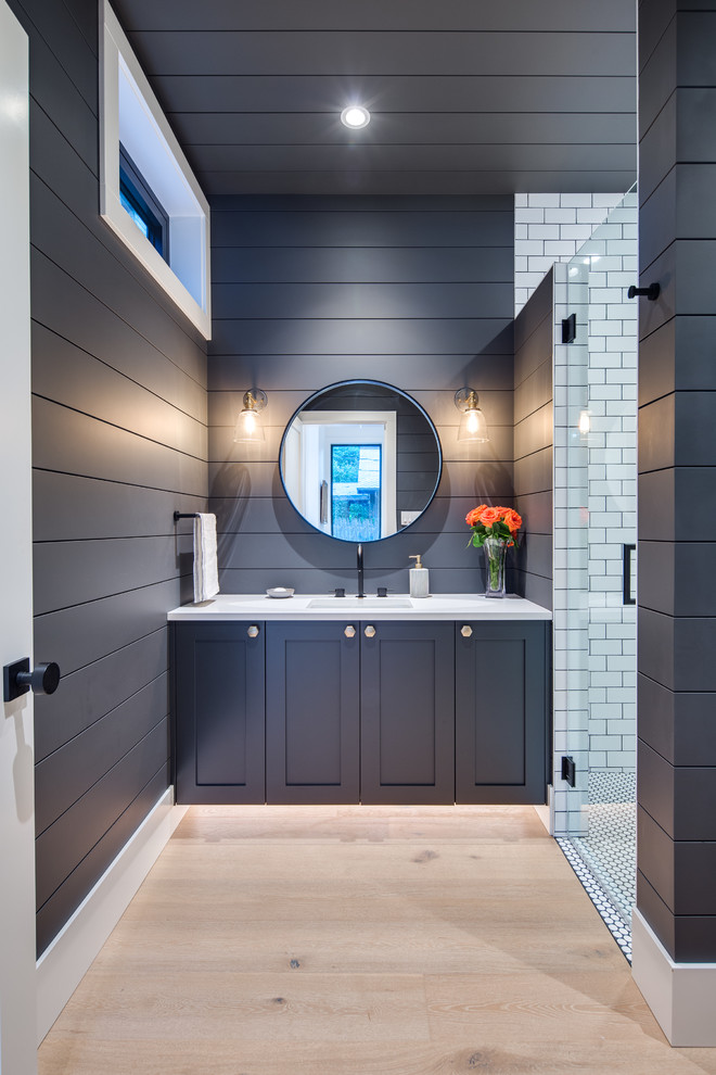 Design ideas for a medium sized modern shower room bathroom in Vancouver with shaker cabinets, blue cabinets, a corner shower, a one-piece toilet, white tiles, blue walls, light hardwood flooring, a submerged sink, quartz worktops, a hinged door and white worktops.