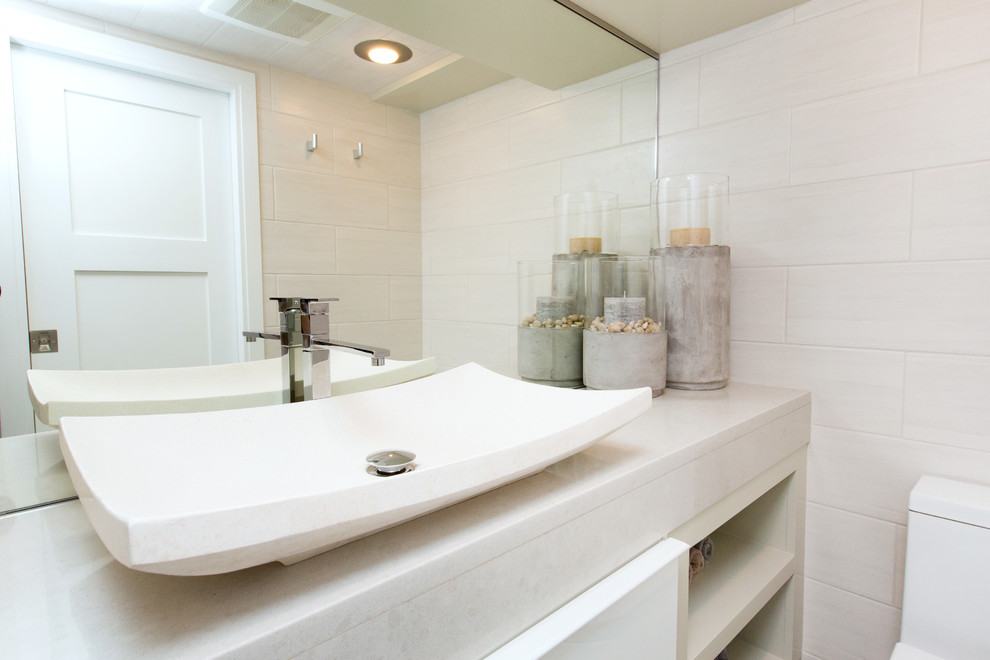 Ejemplo de cuarto de baño contemporáneo de tamaño medio con armarios con paneles lisos, puertas de armario blancas, ducha empotrada, suelo de baldosas tipo guijarro, paredes beige, aseo y ducha y lavabo sobreencimera