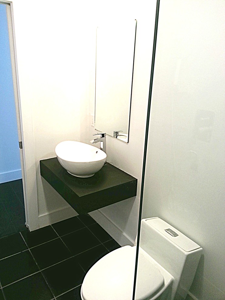 Kleines Modernes Duschbad mit Aufsatzwaschbecken, Waschtisch aus Holz, Toilette mit Aufsatzspülkasten, schwarzen Fliesen, weißer Wandfarbe und Keramikboden in Sonstige