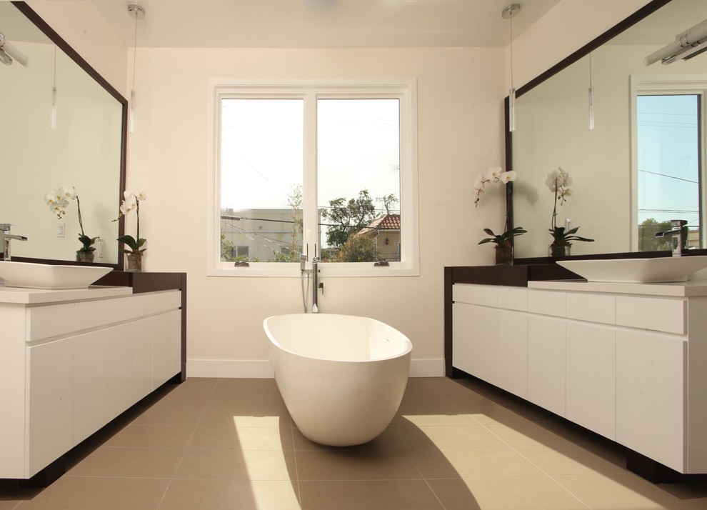 This is an example of a medium sized modern bathroom in Los Angeles with flat-panel cabinets, white cabinets, a freestanding bath, white walls and beige floors.