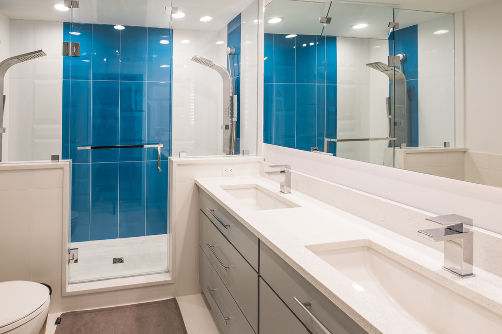 Foto di una stanza da bagno padronale minimalista di medie dimensioni con ante lisce, ante grigie, doccia alcova, WC monopezzo, piastrelle blu, piastrelle di vetro, pareti bianche, lavabo sottopiano, top in quarzite, pavimento bianco e porta doccia a battente