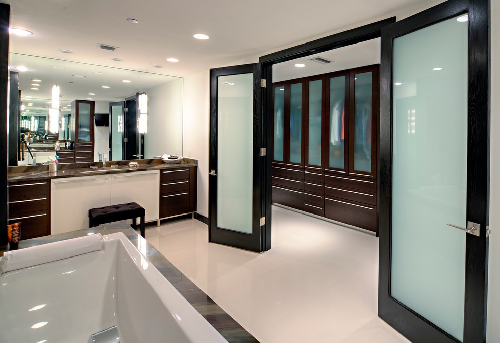 Large minimalist master white tile and porcelain tile porcelain tile, white floor and double-sink drop-in bathtub photo in Tampa with flat-panel cabinets, dark wood cabinets, white walls, an undermount sink, marble countertops, a hinged shower door, black countertops and a built-in vanity