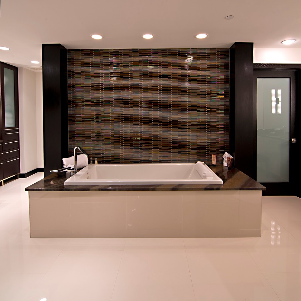 This is an example of a large modern ensuite bathroom in Tampa with flat-panel cabinets, dark wood cabinets, engineered stone worktops, white walls, porcelain flooring, a built-in bath, white tiles and glass tiles.