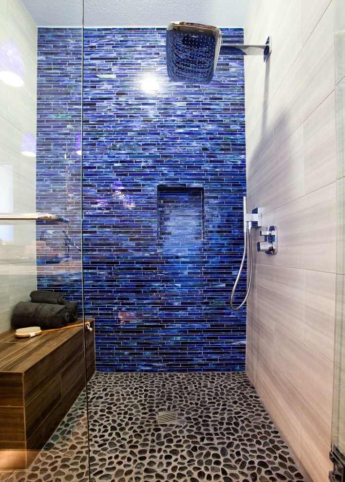 Modern inredning av ett mellanstort en-suite badrum, med en kantlös dusch, blå kakel, glaskakel, vita väggar och klinkergolv i småsten