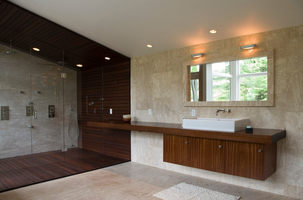Пример оригинального дизайна: большая главная ванная комната в стиле модернизм с плоскими фасадами, темными деревянными фасадами, ванной в нише, душем в нише, бежевой плиткой, бежевыми стенами, полом из керамической плитки, настольной раковиной и столешницей из дерева