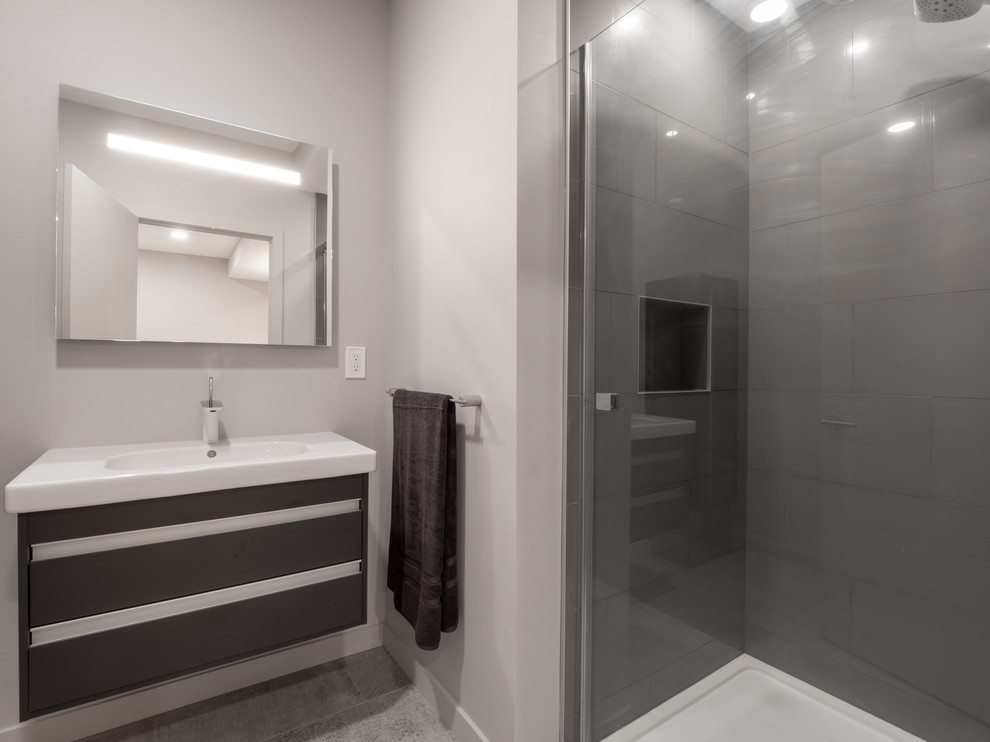 Foto på ett litet funkis vit badrum, med släta luckor, svarta skåp, ett fristående badkar, grå kakel, porslinskakel, grå väggar, laminatgolv, ett integrerad handfat, bänkskiva i kvarts, grått golv och dusch med skjutdörr