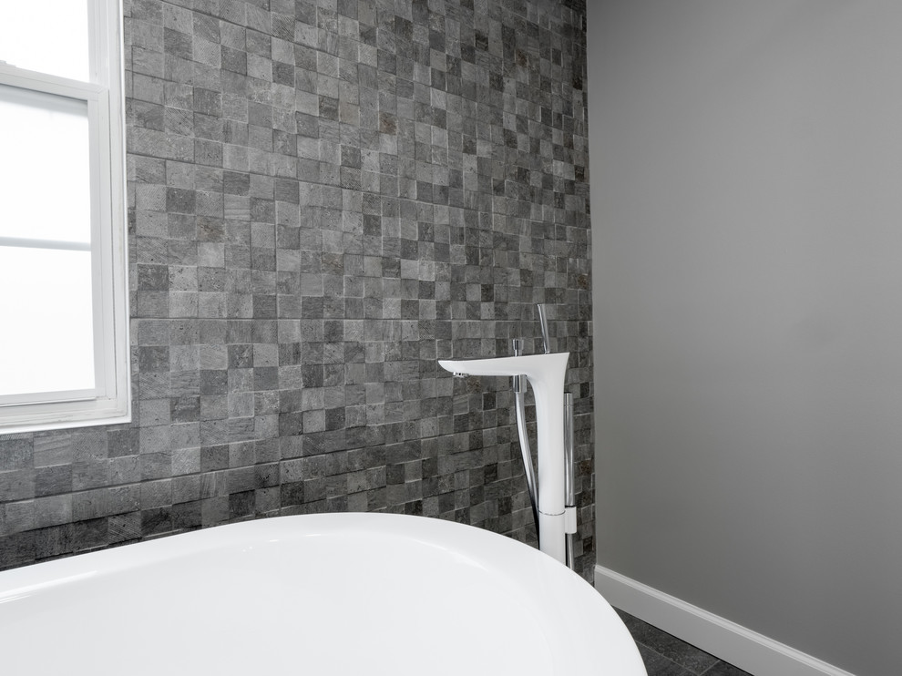 Idéer för stora funkis vitt en-suite badrum, med släta luckor, vita skåp, ett fristående badkar, en dubbeldusch, grå kakel, porslinskakel, grå väggar, klinkergolv i porslin, ett integrerad handfat, bänkskiva i kvarts, grått golv och dusch med skjutdörr