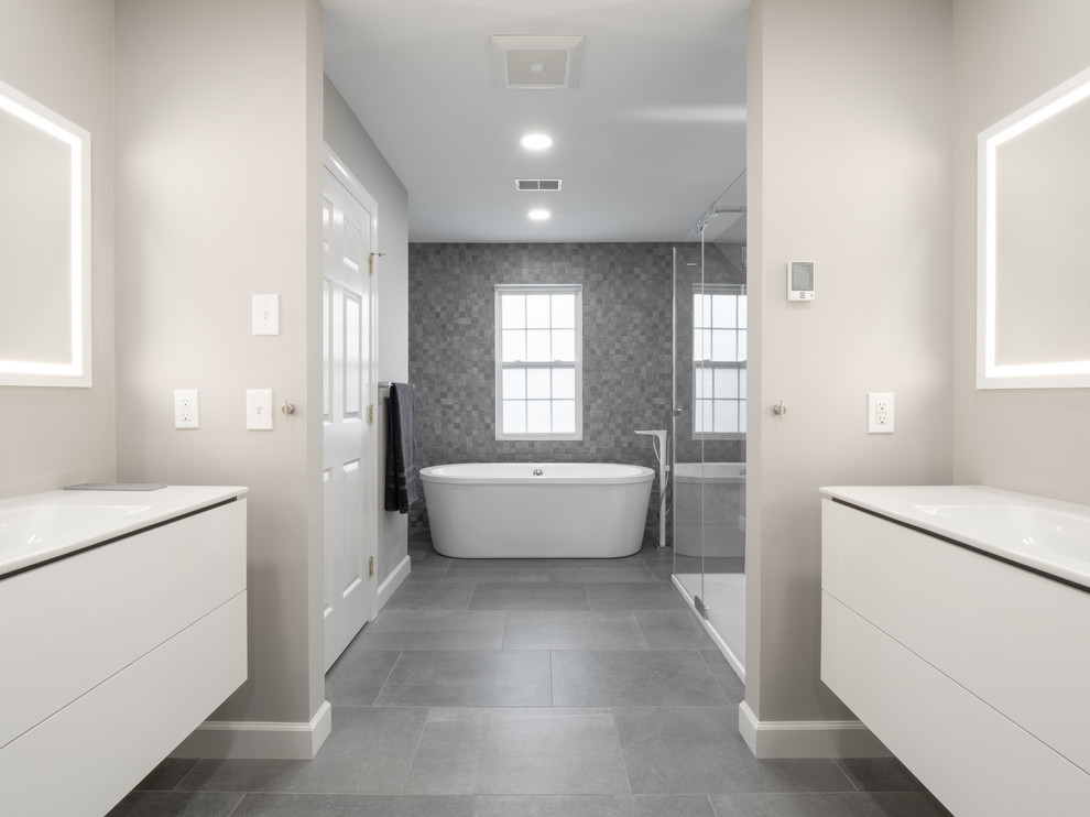 Bild på ett stort funkis vit vitt en-suite badrum, med släta luckor, vita skåp, ett fristående badkar, en dubbeldusch, grå kakel, porslinskakel, grå väggar, klinkergolv i porslin, ett integrerad handfat, bänkskiva i kvarts, grått golv och dusch med skjutdörr