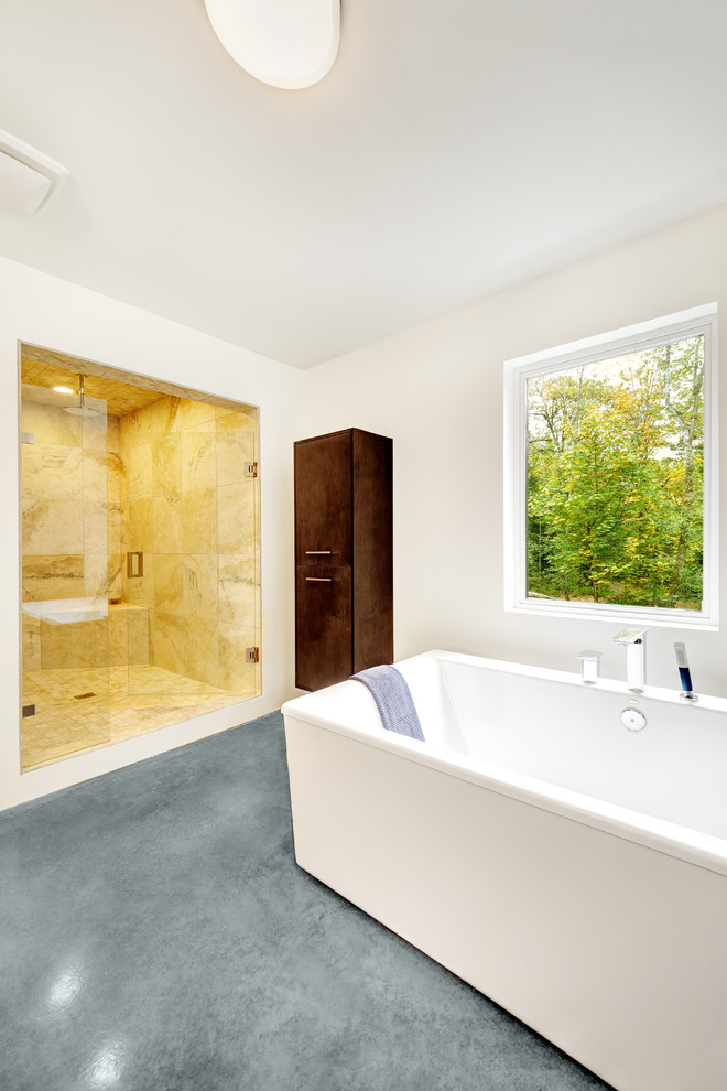 На фото: ванная комната в стиле модернизм с отдельно стоящей ванной и бетонным полом с