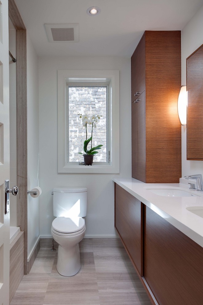 Small modern shower room bathroom in Toronto with a submerged sink, flat-panel cabinets, medium wood cabinets, engineered stone worktops, an alcove bath, an alcove shower, a two-piece toilet, grey tiles, stone slabs, white walls and travertine flooring.