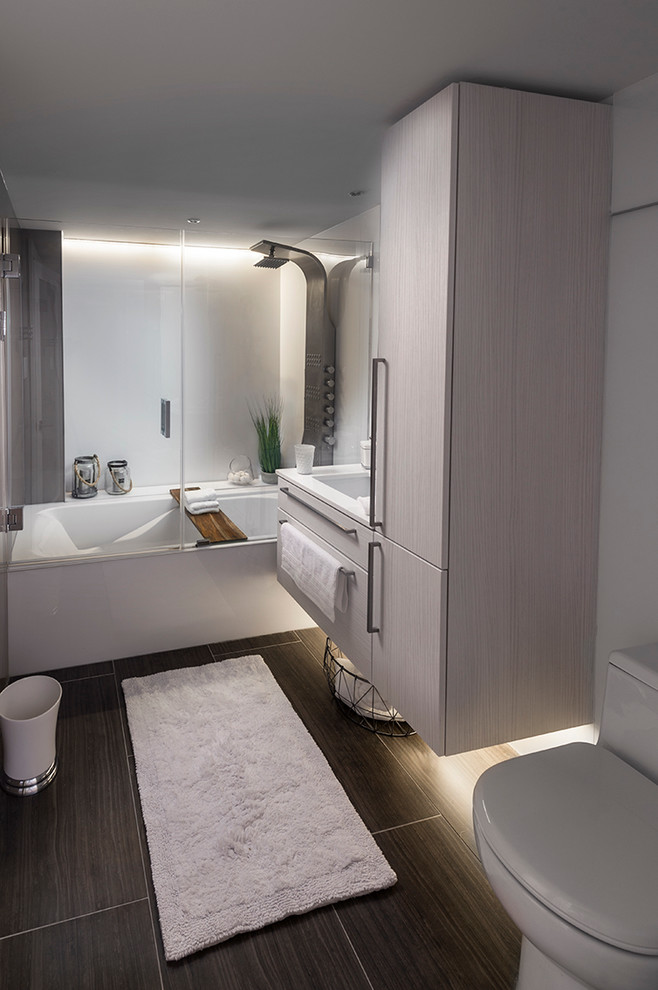 Inspiration for a small modern ensuite bathroom in Philadelphia with flat-panel cabinets, grey cabinets, a built-in bath, a shower/bath combination, a one-piece toilet, white tiles, stone slabs, white walls, slate flooring, a console sink and quartz worktops.