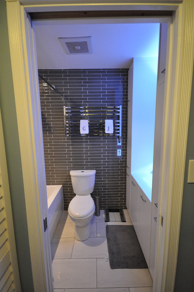 Idee per una piccola stanza da bagno con doccia moderna con lavabo integrato, ante lisce, ante bianche, top in vetro, vasca/doccia, WC a due pezzi, piastrelle marroni, piastrelle di vetro e pavimento in gres porcellanato