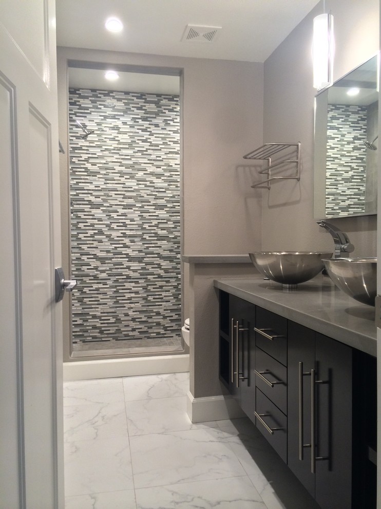 Mid-sized minimalist 3/4 gray tile marble floor alcove shower photo in San Diego with a vessel sink, flat-panel cabinets, dark wood cabinets, quartz countertops, a two-piece toilet and gray walls