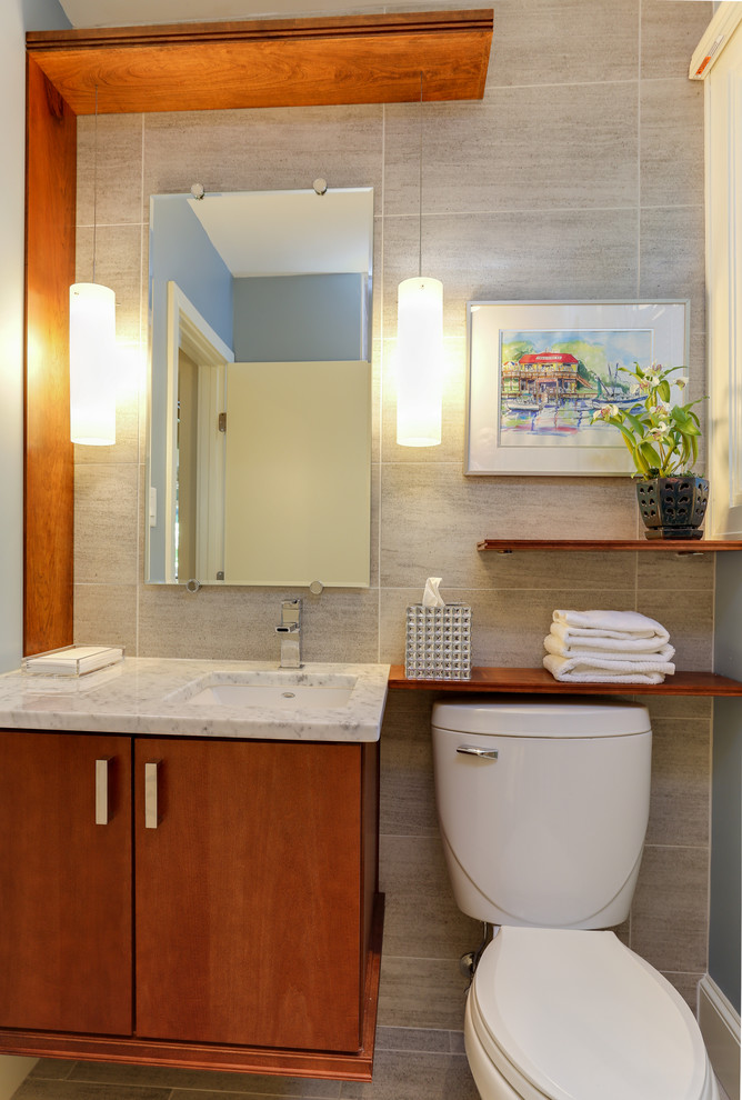 Cette image montre une petite salle de bain minimaliste en bois brun avec un lavabo encastré, un placard à porte plane, un plan de toilette en marbre, WC séparés, un carrelage gris, des carreaux de céramique, un mur bleu et un sol en carrelage de céramique.