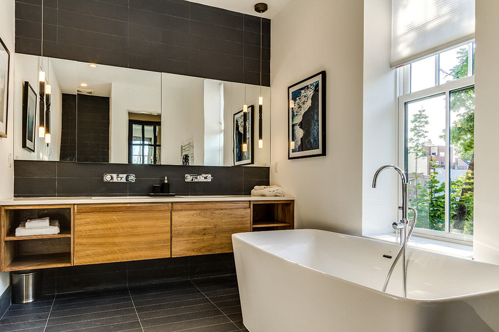 На фото: главная ванная комната в современном стиле с плоскими фасадами, фасадами цвета дерева среднего тона, серыми стенами, черным полом, серой столешницей и зеркалом с подсветкой