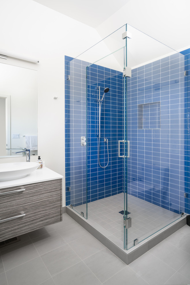 Идея дизайна: ванная комната среднего размера в стиле модернизм с фасадами с филенкой типа жалюзи, серыми фасадами, угловым душем, синей плиткой, керамической плиткой, белыми стенами, полом из керамической плитки, консольной раковиной, столешницей из искусственного камня, серым полом и душем с распашными дверями