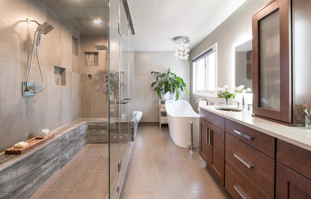 Exempel på ett mellanstort modernt en-suite badrum, med släta luckor, skåp i mellenmörkt trä, ett fristående badkar, en dubbeldusch, grå väggar, ett integrerad handfat, bänkskiva i akrylsten, en toalettstol med hel cisternkåpa, grå kakel, cementkakel, klinkergolv i porslin, beiget golv och dusch med gångjärnsdörr