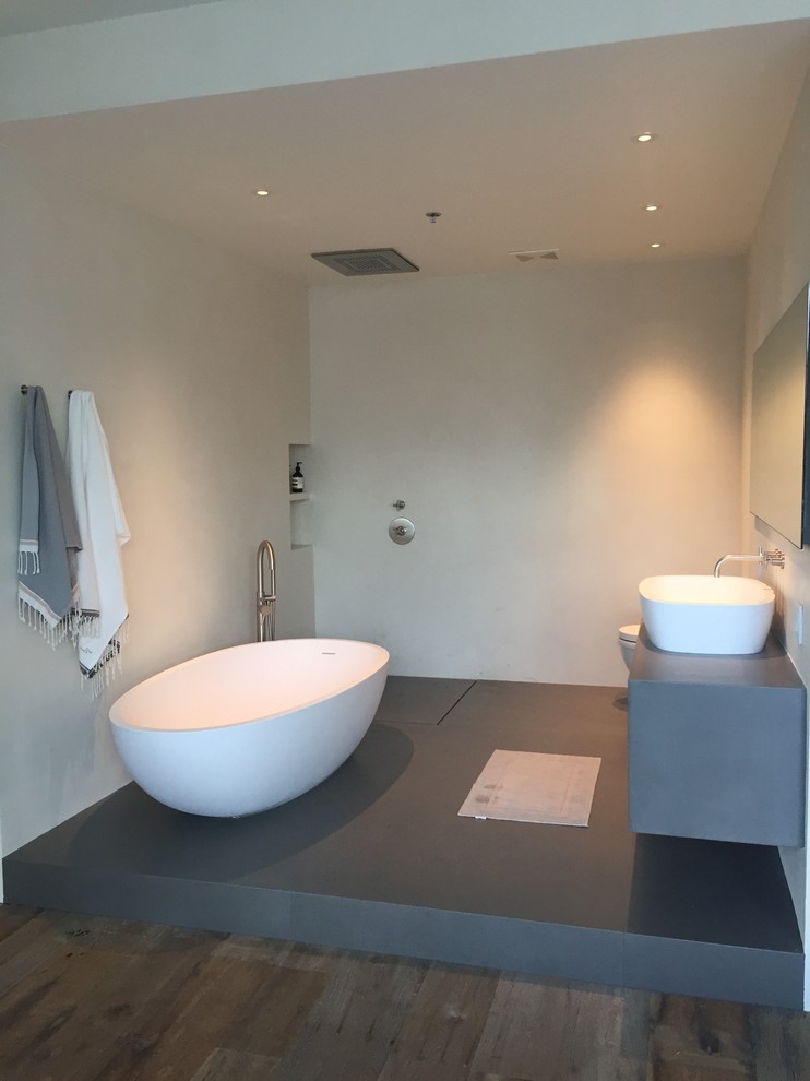 Idéer för mellanstora funkis en-suite badrum, med öppna hyllor, grå skåp, ett fristående badkar, en öppen dusch, en toalettstol med hel cisternkåpa, ett fristående handfat, vita väggar, betonggolv och bänkskiva i betong