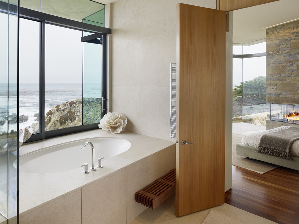 Exemple d'une salle de bain tendance avec une baignoire encastrée, un carrelage beige et une fenêtre.