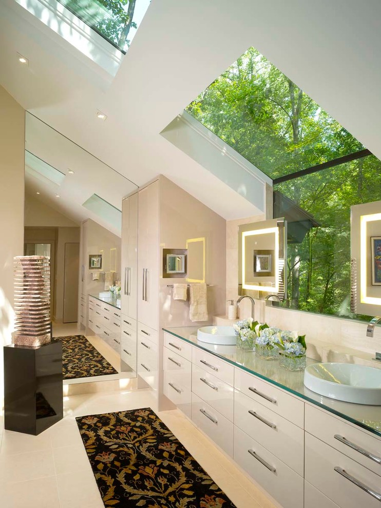 Пример оригинального дизайна: большая главная ванная комната в современном стиле с плоскими фасадами, белыми фасадами, белыми стенами, полом из керамогранита, настольной раковиной, стеклянной столешницей, угловым душем, бежевой плиткой и каменной плиткой