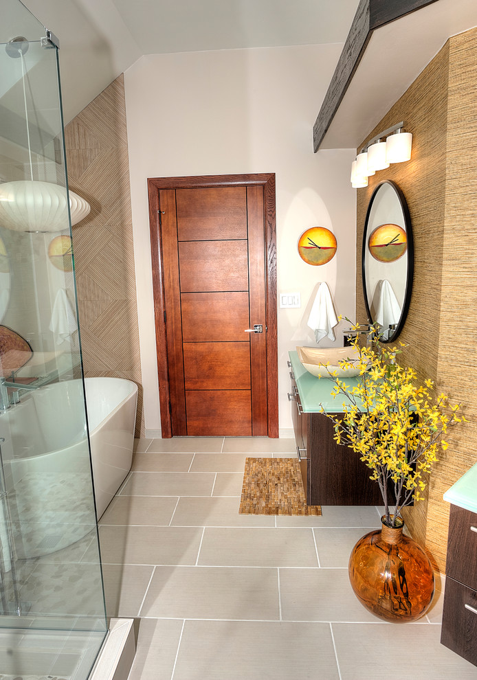 На фото: главная ванная комната среднего размера в стиле модернизм с плоскими фасадами, коричневыми фасадами, отдельно стоящей ванной, угловым душем, унитазом-моноблоком, бежевой плиткой, керамогранитной плиткой, коричневыми стенами, полом из галечной плитки, настольной раковиной, стеклянной столешницей, бежевым полом, душем с распашными дверями и зеленой столешницей