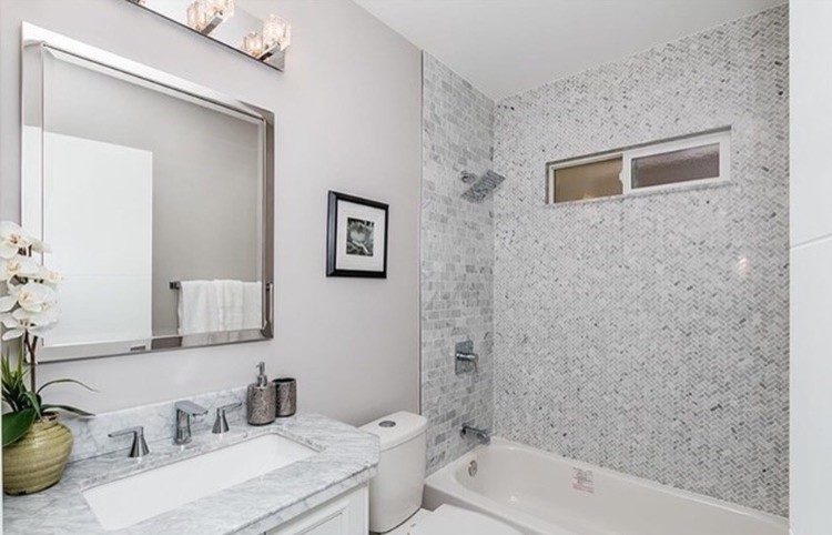 На фото: ванная комната среднего размера в стиле модернизм с белыми фасадами, ванной в нише, душем над ванной, раздельным унитазом, серыми стенами, душевой кабиной, врезной раковиной, мраморной столешницей, фасадами с выступающей филенкой, серой плиткой, плиткой мозаикой и шторкой для ванной