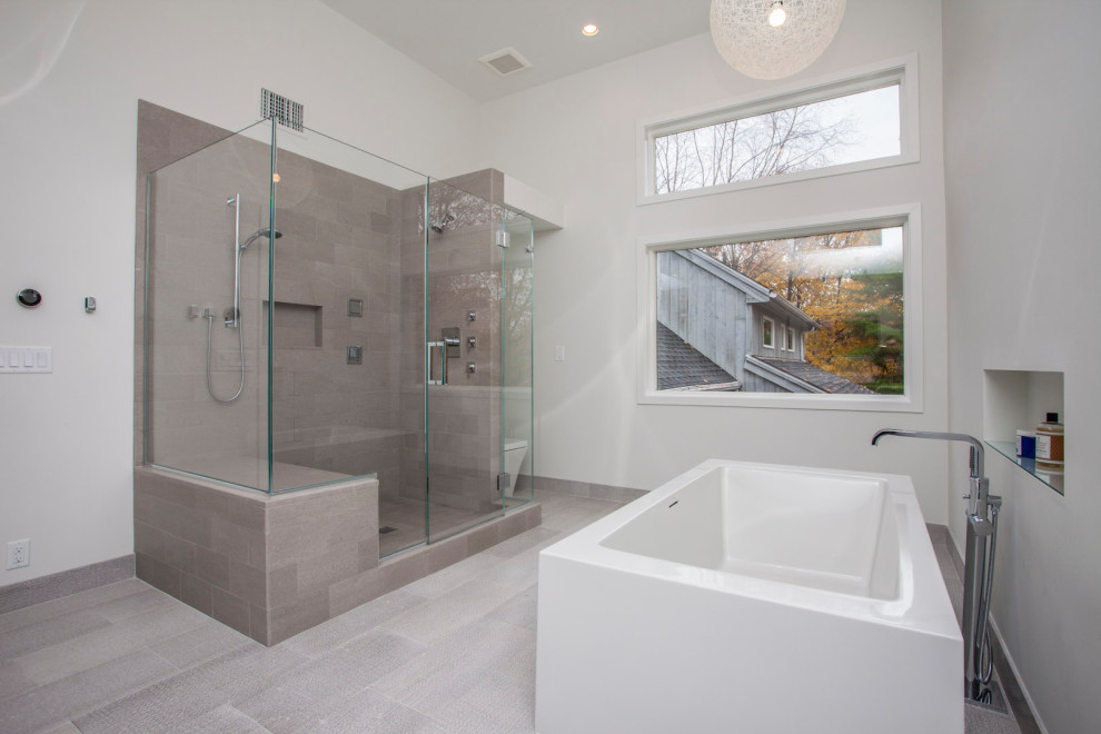 Inspiration for a large modern master gray tile and stone tile double-sink freestanding bathtub remodel in New York with flat-panel cabinets, medium tone wood cabinets, a wall-mount sink, a hinged shower door, white countertops and a floating vanity