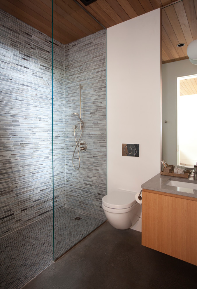 Foto på ett funkis grå badrum, med en kantlös dusch, blå kakel, stickkakel och betonggolv